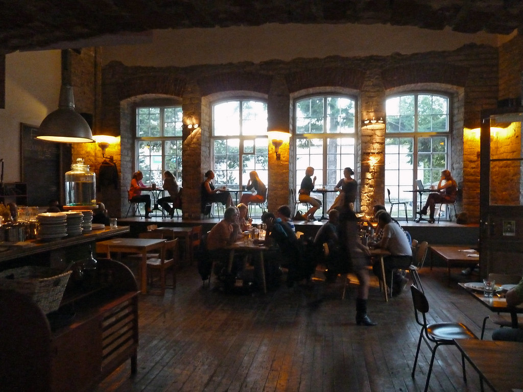 Warmly lit industrial interior of F-Hoone beneath tall arched windows